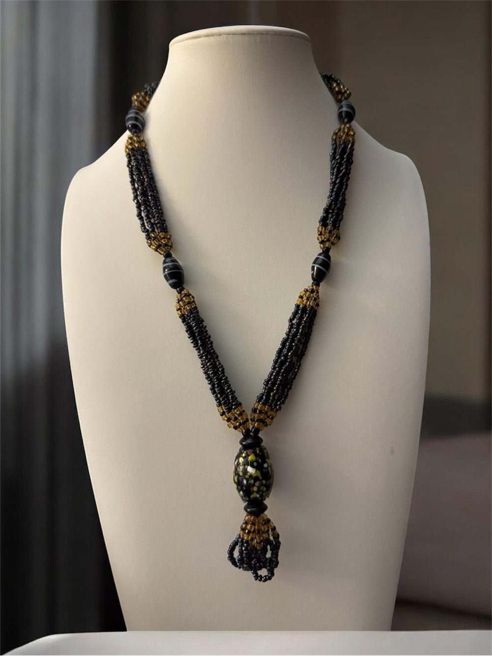 Vintage multi strand seed bead necklace with a prominent central focal pendant